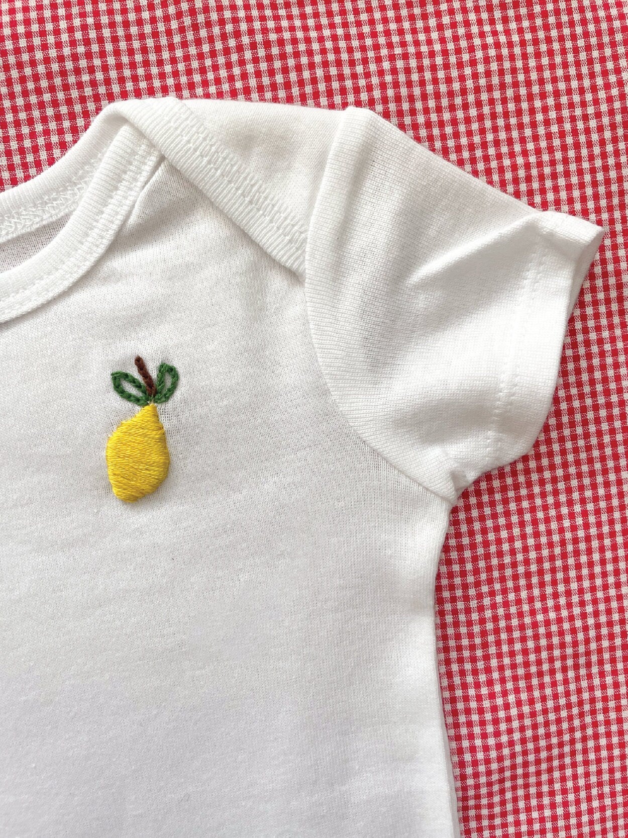 Lemon hand embroidery on white baby onesie