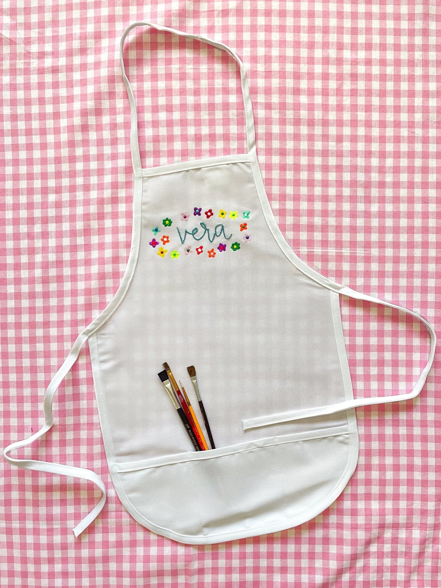 Kids apron embroidered with painted flowers around the name