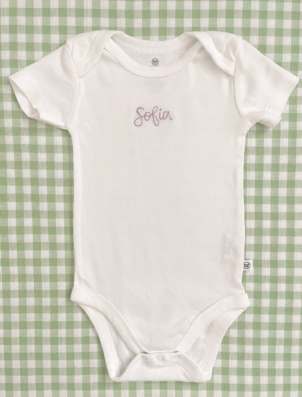 Hand embroidered baby bodysuit featuring baby's name in center of chest