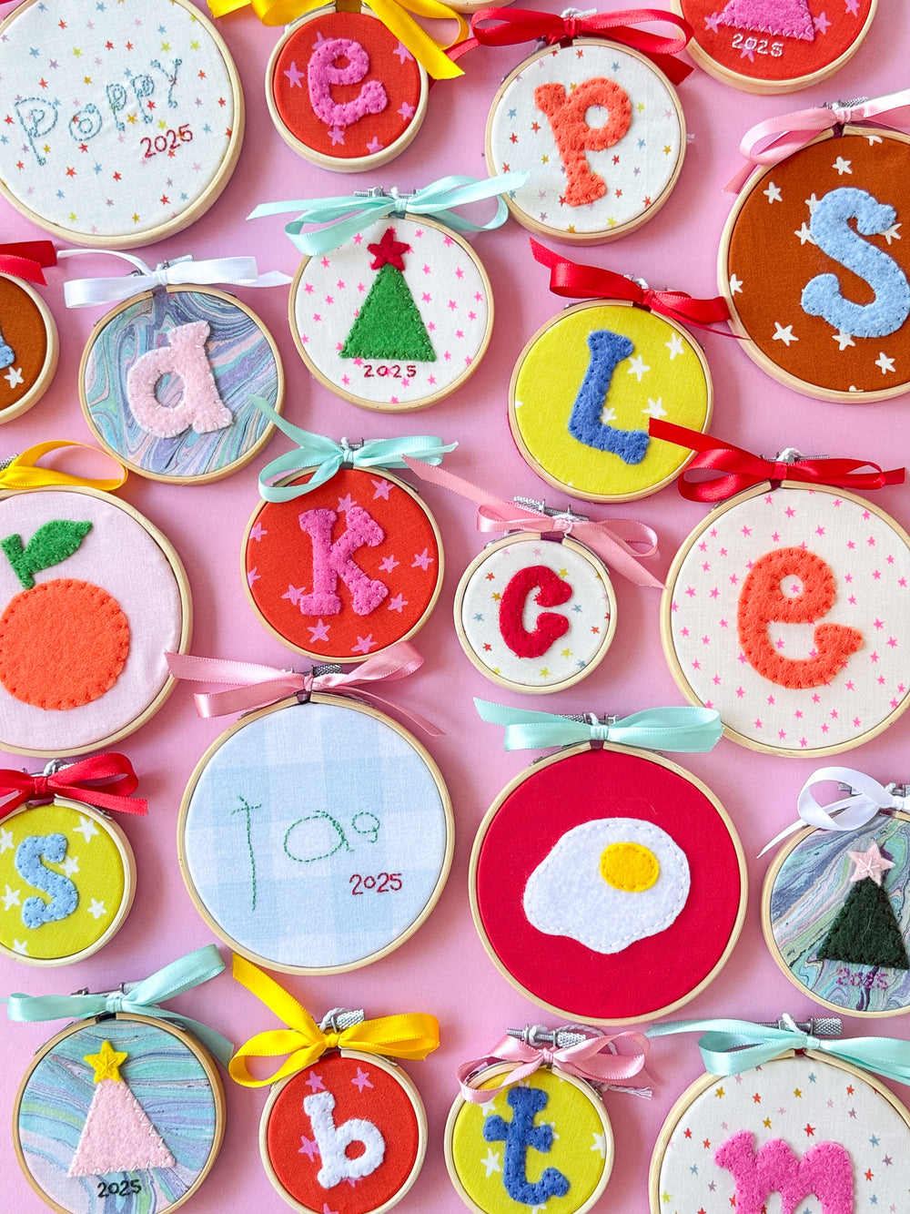 Colorful Hand Embroidered felt ornaments on a light pink backdrop
