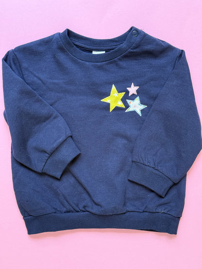 Navy blue kid'sweatshirt with colorful star applique designs on a pink background