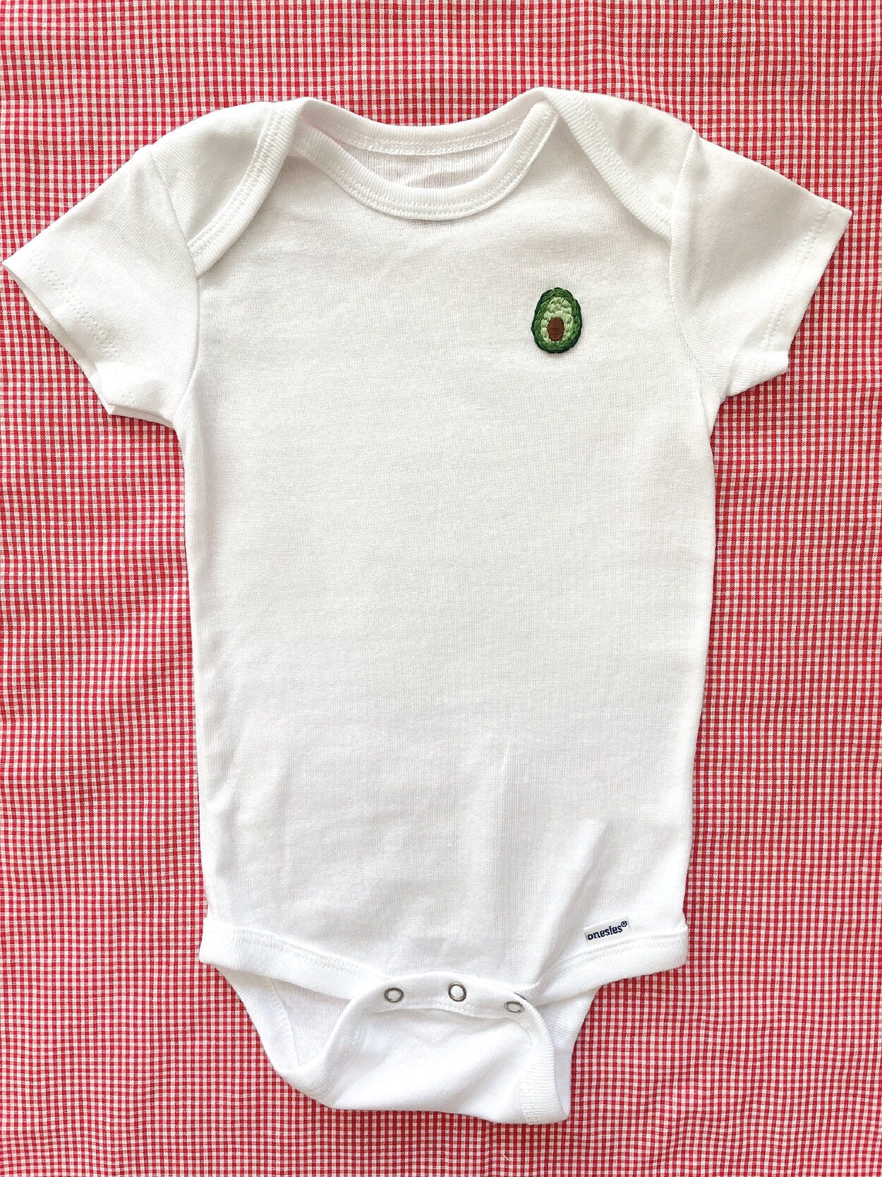 Avocado hand embroidery on white baby onesie