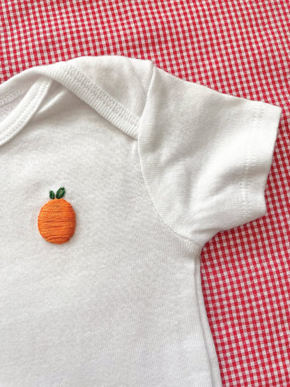 Orange hand embroidery on white baby onesie