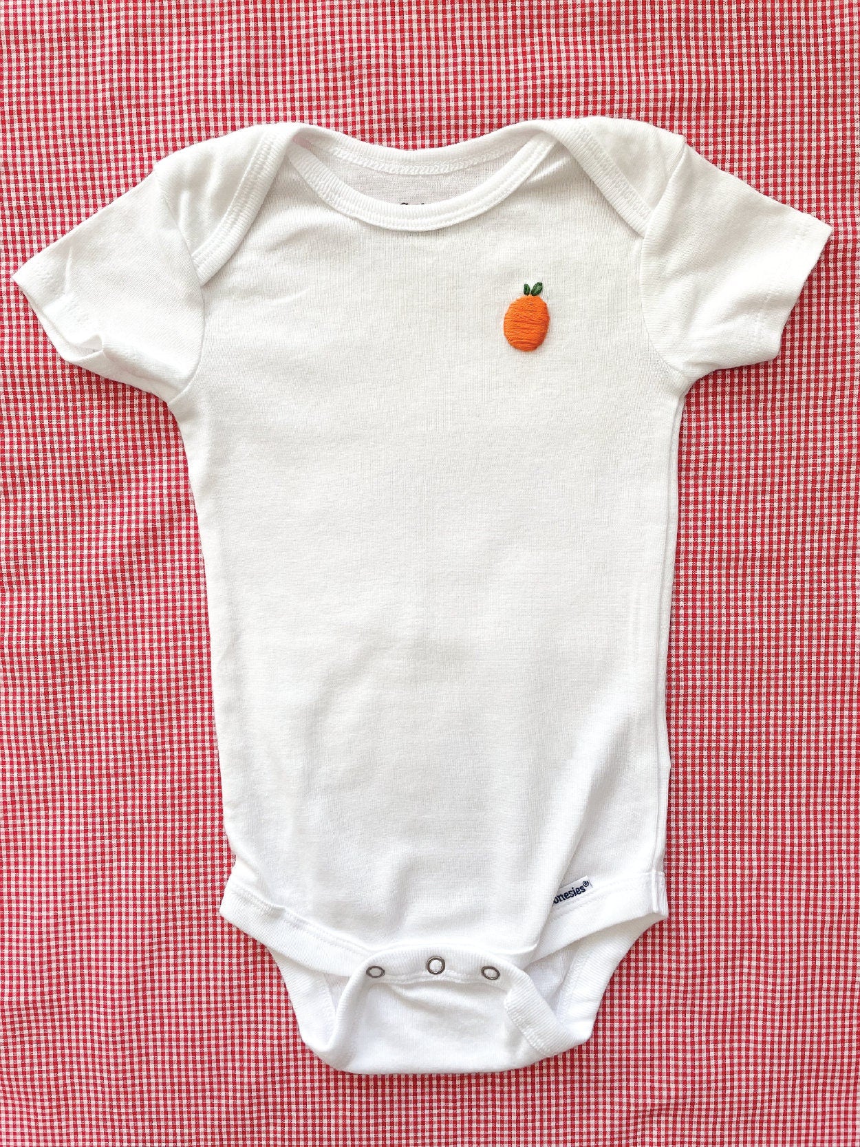 Orange hand embroidery on white baby onesie