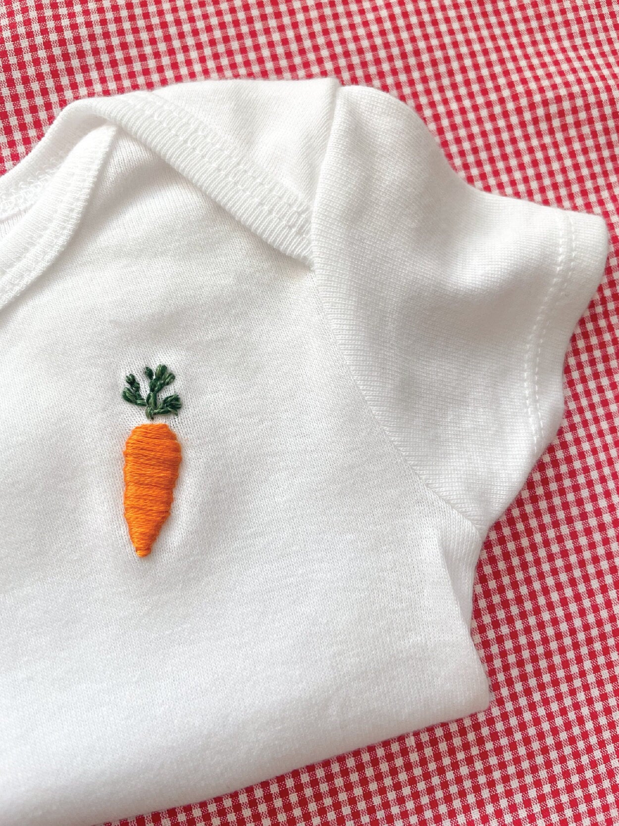 carrot hand embroidery on white baby onesie