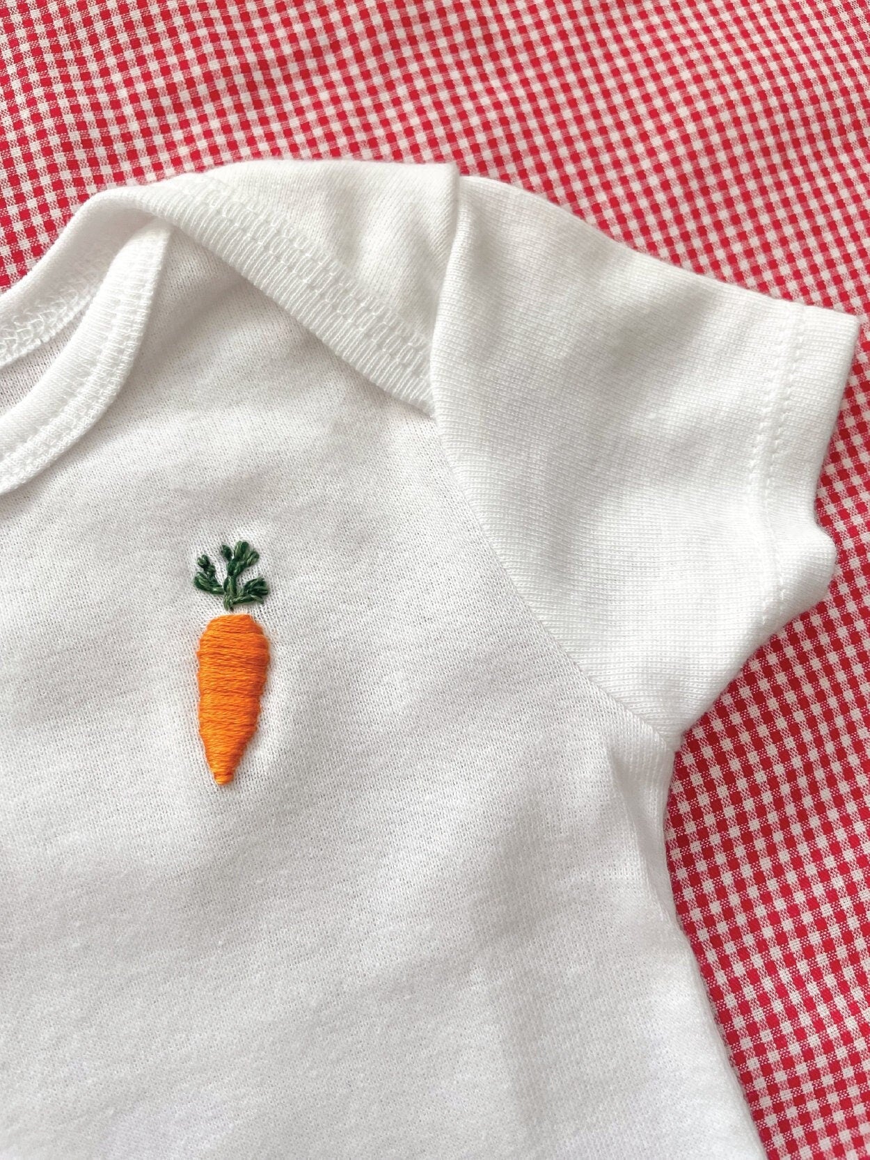 carrot hand embroidery on white baby onesie