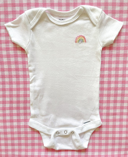 Fully body image of hand embroidered onesie featuring rainbow design in bright colors on left chest