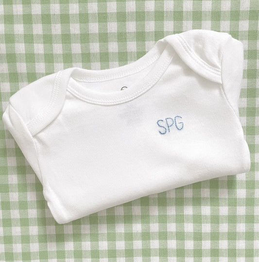 Three initials hand embroidered on left corner of white bodysuit